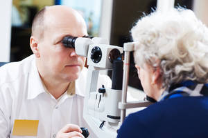 Picture of optometrist giving an eye exam to an elderly lady.